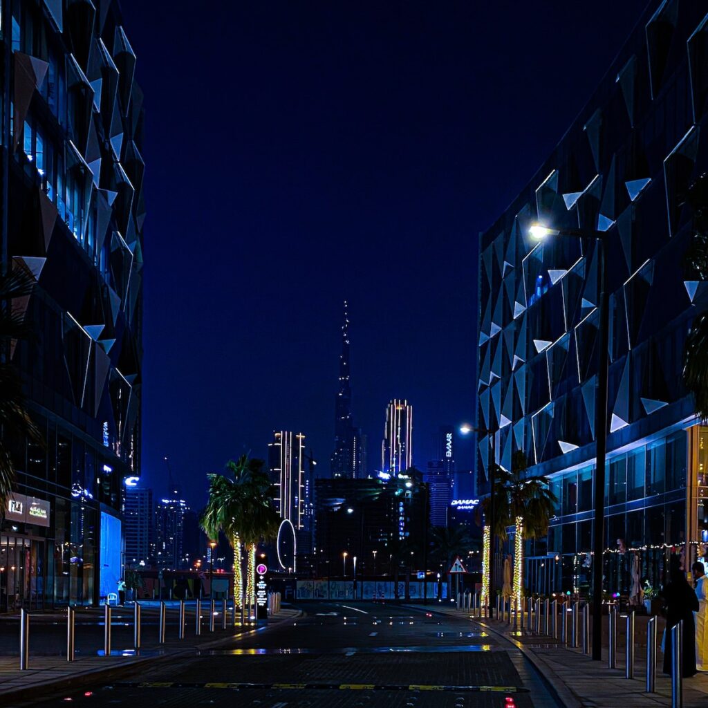 people walking on sidewalk near high rise buildings during night time